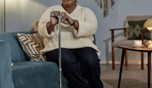 Elderly black woman with a cane sitting on sofa