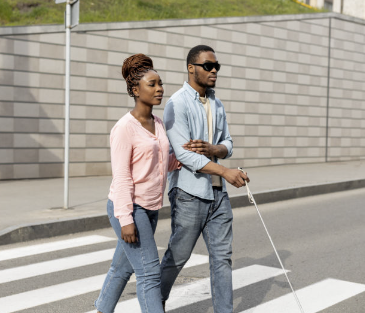 Blind man being led across the street by a female companion