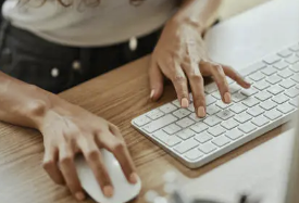 Woman's hands on keyboard and mouse of a desktop computer