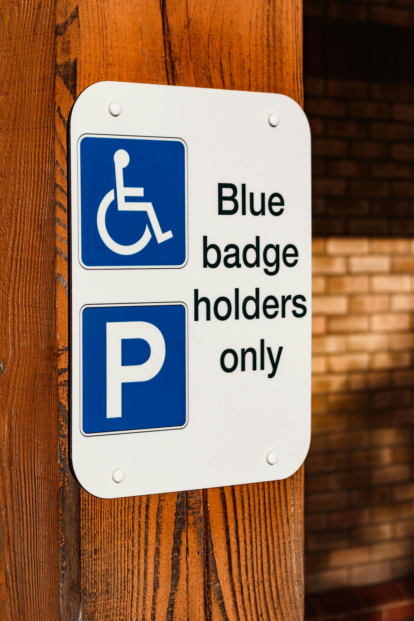 A blue badge parking sign mounted on a wooden post indicating reserved parking for disabled access.